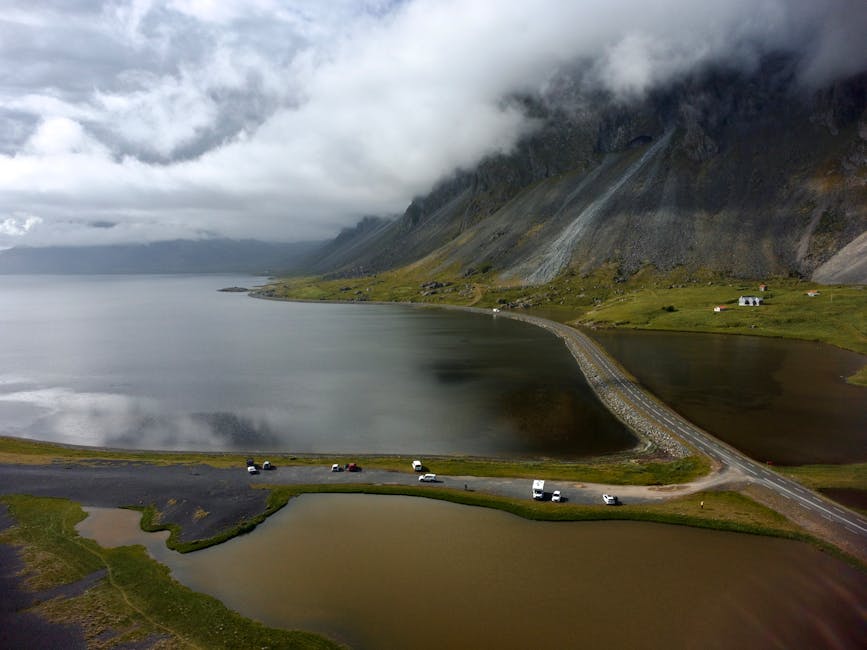 Captivating aerial shot of a serene Icelandic lake surrounded by dramatic mountains and clouds.