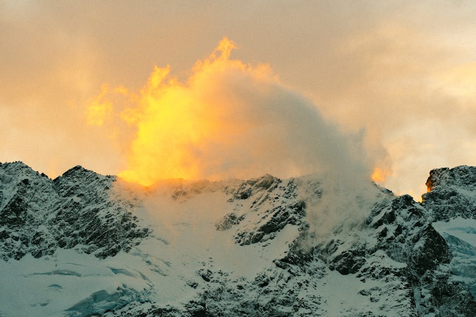 Golden sunrise illuminating snow-covered mountains in New Zealand, creating a dramatic and scenic view.